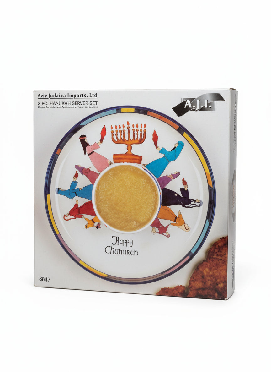 Box with a colorful design of people around a table with a bowl, labeled 'Happy Hanukkah', on a patterned surface.